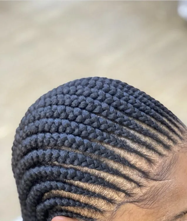 Neat cornrows curving around the side of the head, close-up