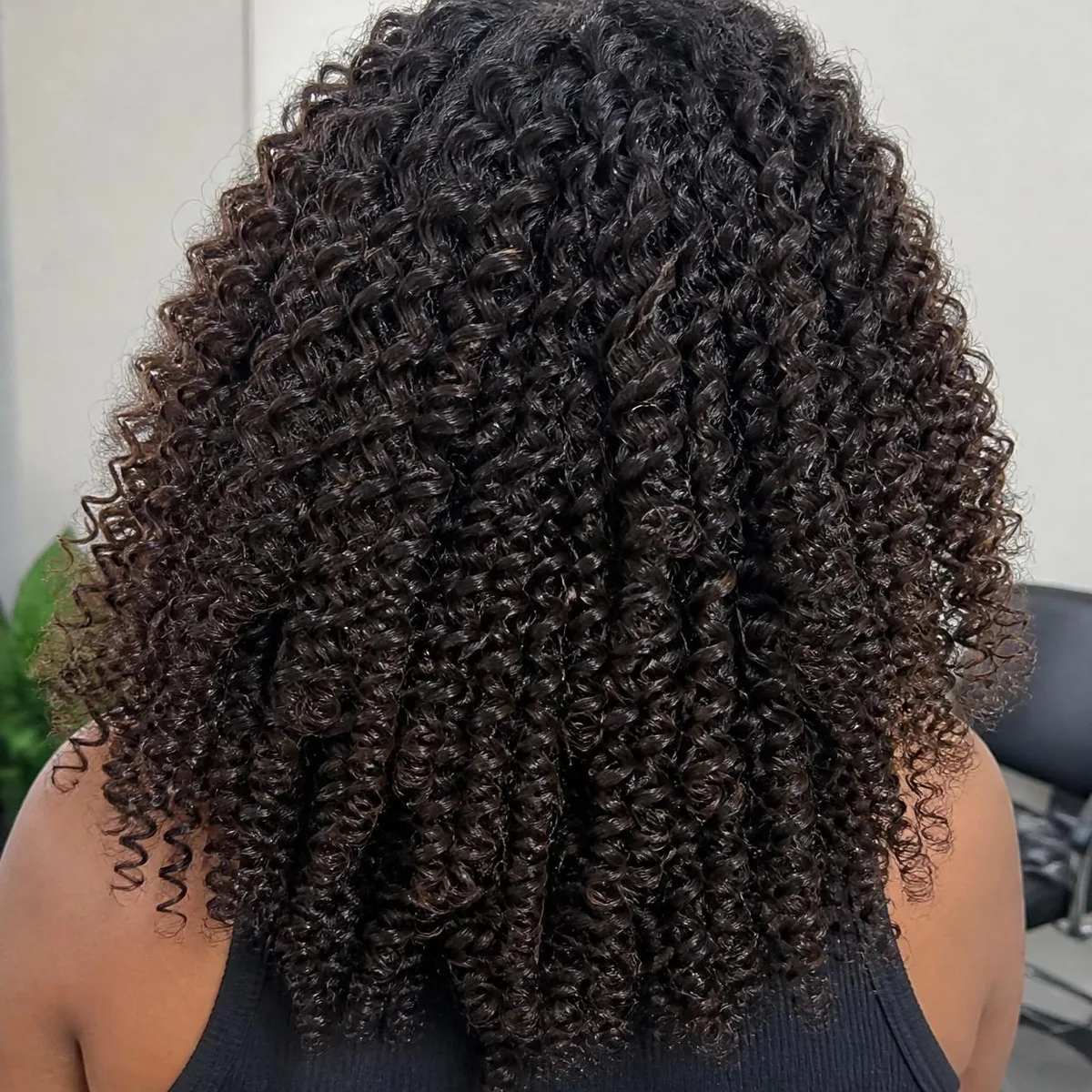 Full, shoulder-length curly crochet style in dark brown, seen from the back